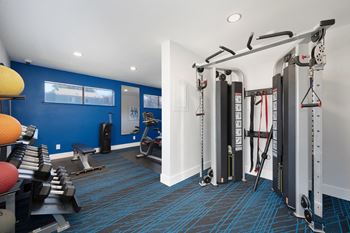 A gym with weights machines and other exercise equipment in a room